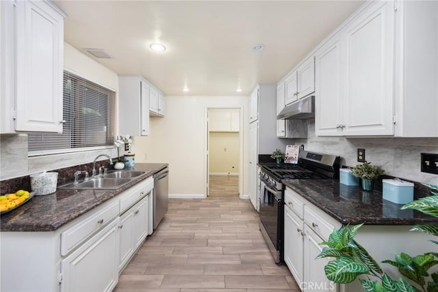 kitchen featuring appliances with stainless steel finishes, dark stone countertops, white cabinets, and sink