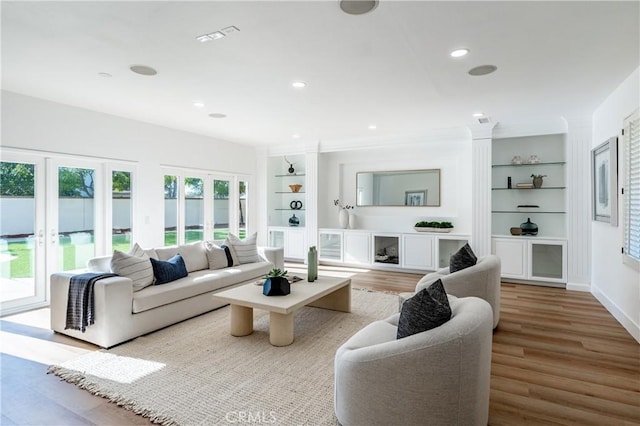 living room featuring french doors, built in features, and light hardwood / wood-style flooring