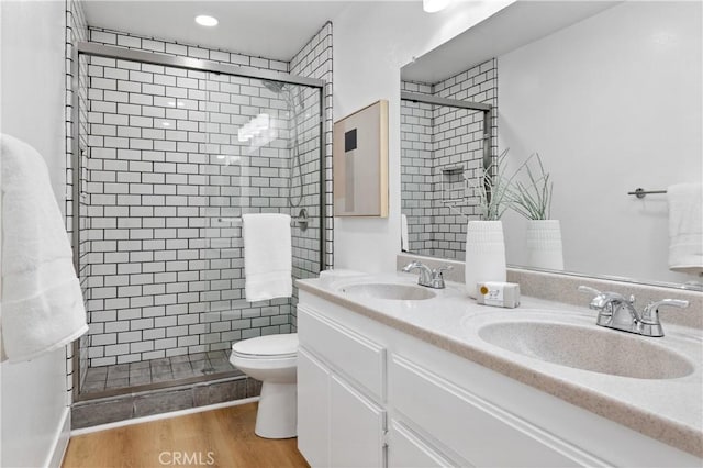 bathroom featuring vanity, toilet, hardwood / wood-style floors, and a shower with shower door