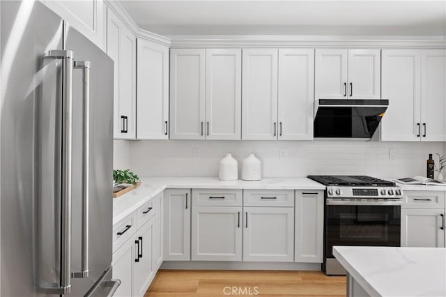 kitchen with light hardwood / wood-style flooring, appliances with stainless steel finishes, extractor fan, light stone countertops, and white cabinets