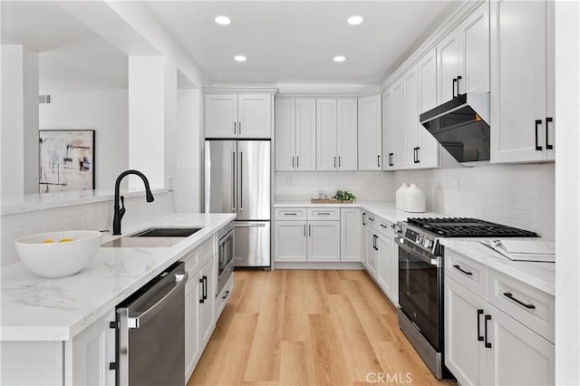 kitchen featuring sink, light hardwood / wood-style flooring, appliances with stainless steel finishes, light stone countertops, and white cabinets