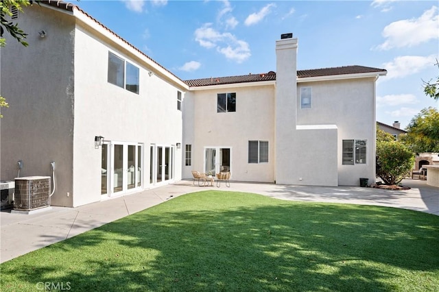 rear view of house with cooling unit, a yard, and a patio