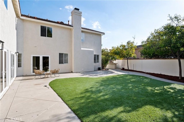 back of house featuring a lawn and a patio