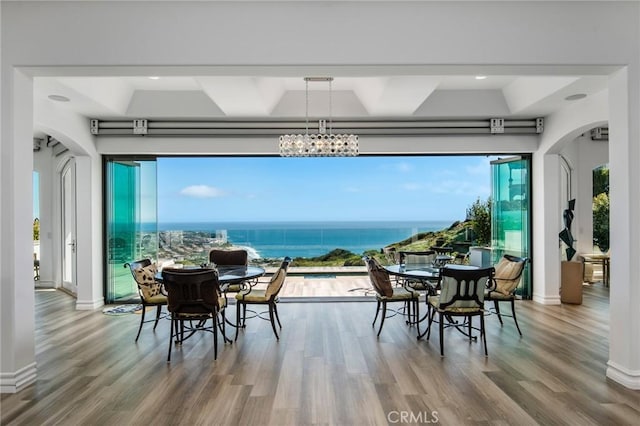 dining space with a water view, wood-type flooring, and a notable chandelier