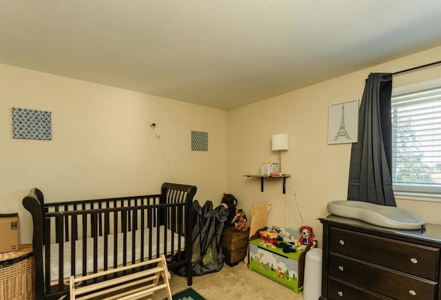 carpeted bedroom featuring a nursery area