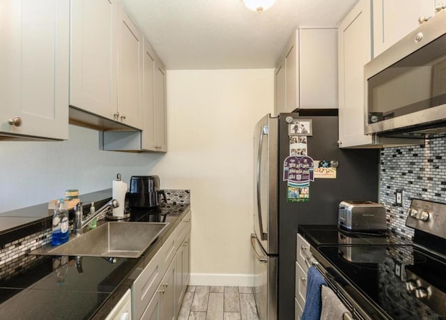 kitchen featuring appliances with stainless steel finishes, sink, white cabinets, and decorative backsplash