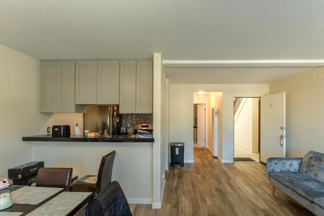 kitchen with tasteful backsplash, gray cabinetry, stainless steel fridge, and light wood-type flooring