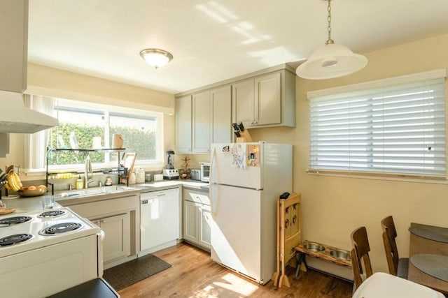 kitchen with range hood, decorative light fixtures, sink, white appliances, and light wood-type flooring