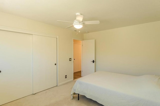 bedroom with light colored carpet, a closet, and ceiling fan