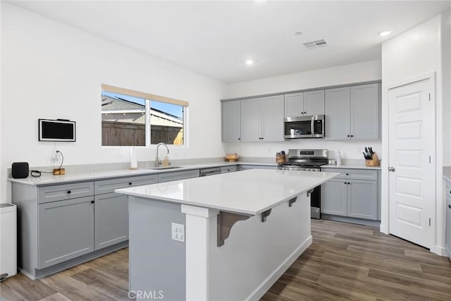 kitchen featuring appliances with stainless steel finishes, sink, gray cabinetry, and a center island