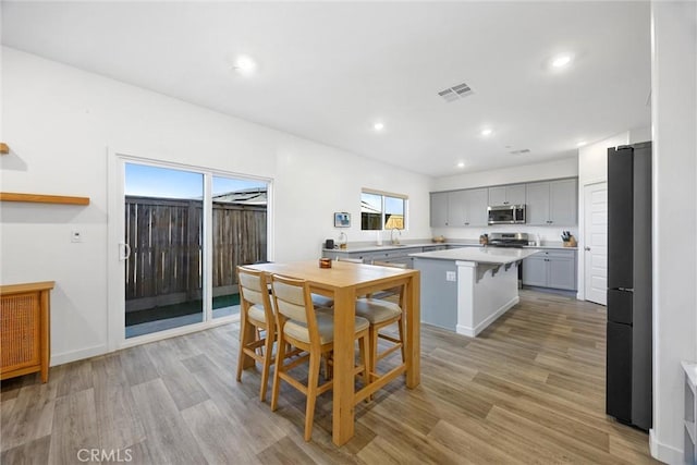 kitchen featuring a center island, gray cabinetry, stainless steel appliances, and light hardwood / wood-style flooring