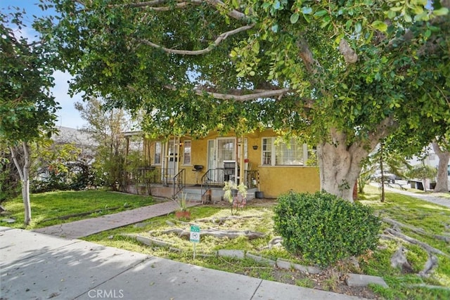 obstructed view of property with a front lawn and stucco siding