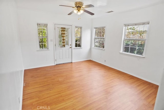 unfurnished room with light wood-style floors, baseboards, visible vents, and a ceiling fan