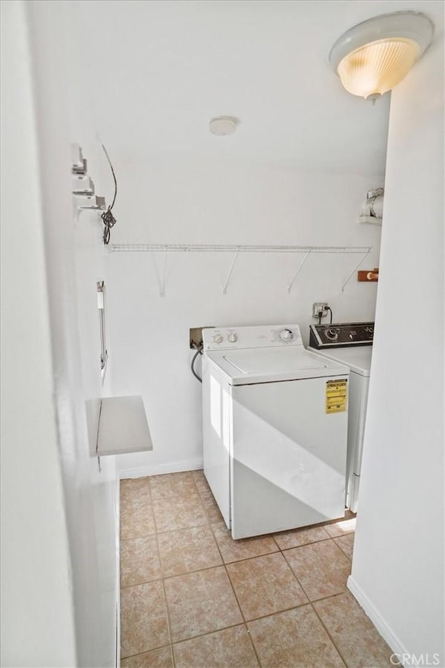 clothes washing area featuring laundry area, baseboards, washer and dryer, and light tile patterned flooring