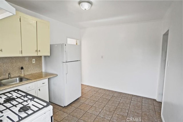 kitchen featuring light tile patterned floors, white appliances, a sink, light countertops, and tasteful backsplash