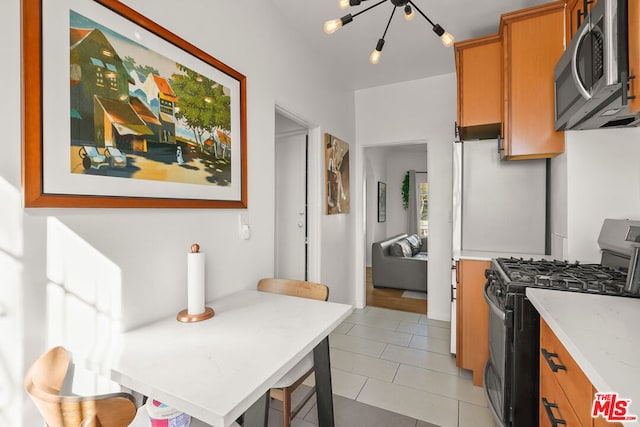 kitchen with light tile patterned floors, a breakfast bar area, stainless steel appliances, and light stone countertops