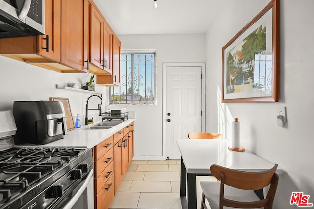 kitchen with light tile patterned floors, appliances with stainless steel finishes, and sink