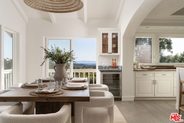 dining room featuring light hardwood / wood-style floors, beamed ceiling, a mountain view, and wine cooler