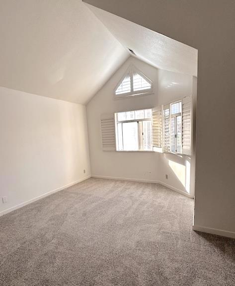 bonus room with vaulted ceiling and carpet flooring