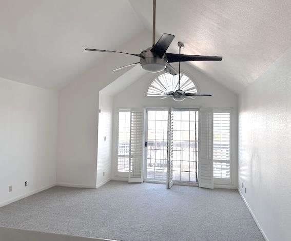 carpeted empty room featuring ceiling fan and vaulted ceiling