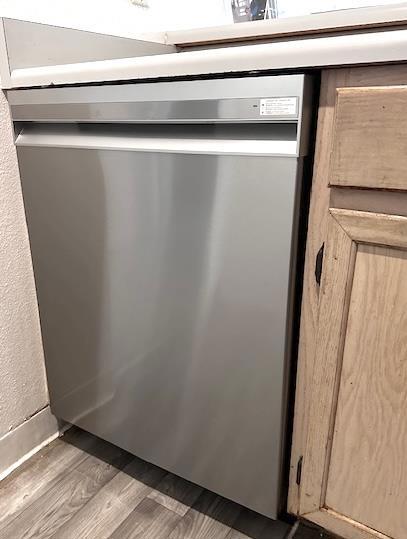 interior details with wood-type flooring and stainless steel dishwasher