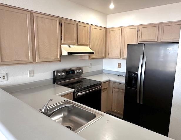 kitchen with sink, light brown cabinets, refrigerator with ice dispenser, and stainless steel electric range