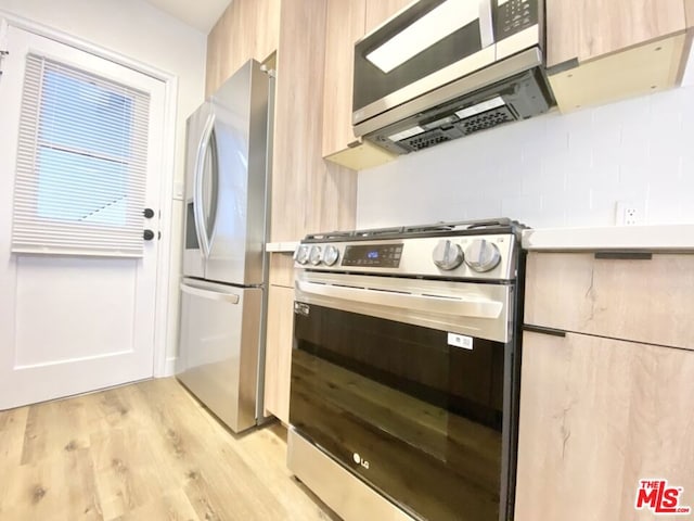 kitchen featuring appliances with stainless steel finishes, light brown cabinetry, and light hardwood / wood-style floors