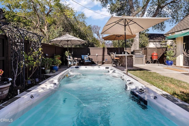 view of swimming pool featuring exterior kitchen and a hot tub