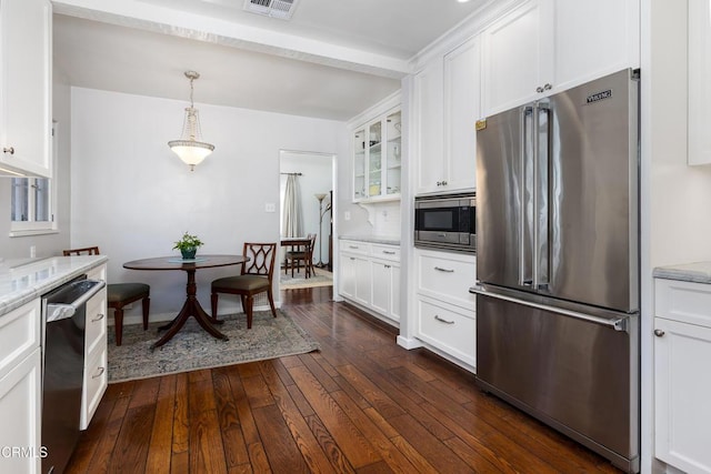 kitchen with appliances with stainless steel finishes, dark hardwood / wood-style flooring, white cabinets, and light stone counters