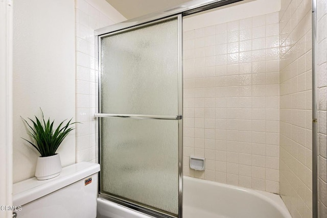 full bath featuring toilet and combined bath / shower with glass door