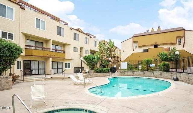 pool with a patio area and fence