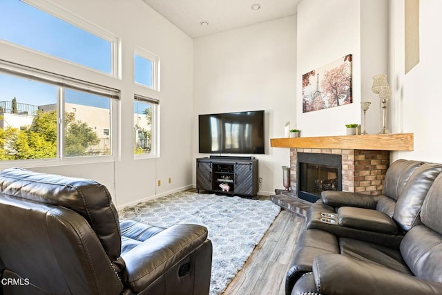 living room with a high ceiling, wood finished floors, baseboards, and a fireplace
