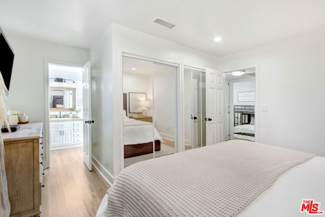 bedroom featuring sink, light wood-type flooring, and two closets