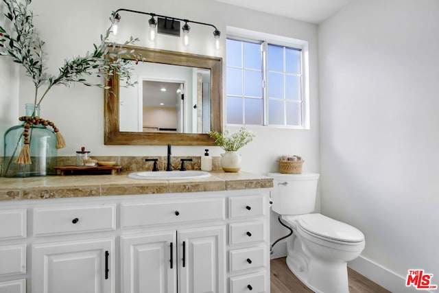 bathroom with hardwood / wood-style floors, toilet, and vanity