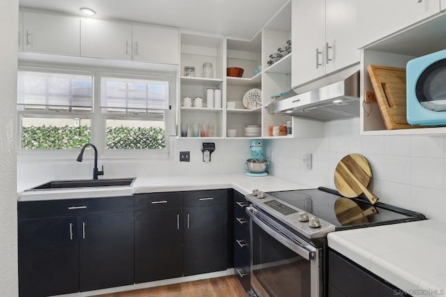 kitchen featuring stainless steel range with electric stovetop, light hardwood / wood-style floors, tasteful backsplash, white cabinets, and sink