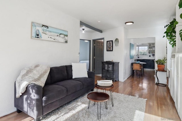 living room with ceiling fan, dark wood-type flooring, and beam ceiling