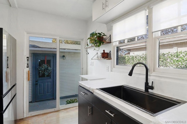 kitchen featuring light wood-type flooring, stainless steel refrigerator with ice dispenser, and sink