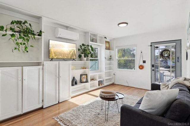 living room featuring an AC wall unit and light hardwood / wood-style flooring