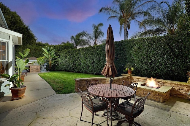 patio terrace at dusk with a lawn and an outdoor fire pit