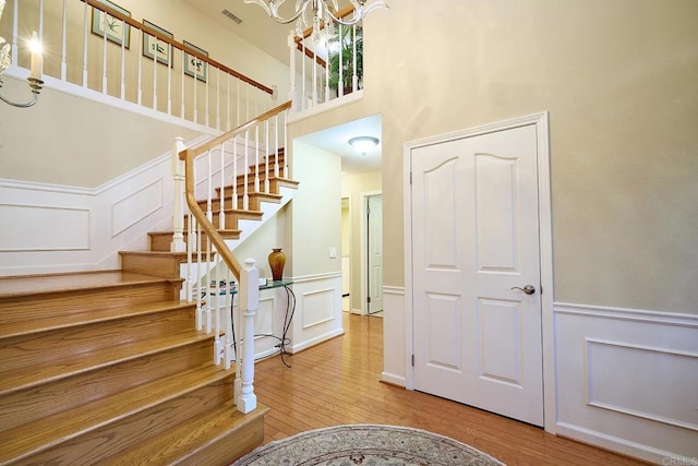 stairs featuring a high ceiling, an inviting chandelier, and hardwood / wood-style flooring