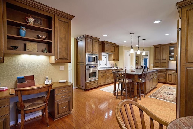 kitchen featuring a breakfast bar area, stainless steel appliances, pendant lighting, light hardwood / wood-style flooring, and a center island