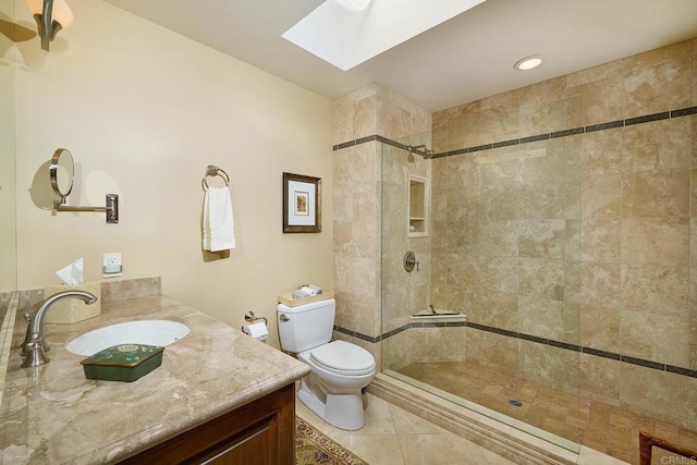 bathroom with tiled shower, vanity, a skylight, and toilet