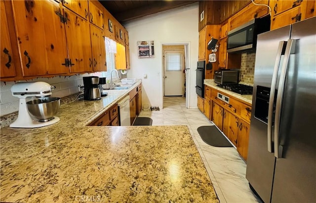 kitchen featuring brown cabinetry, a sink, lofted ceiling with beams, and black appliances