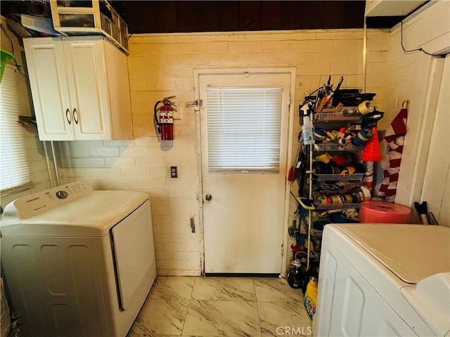 washroom featuring marble finish floor, independent washer and dryer, and cabinet space