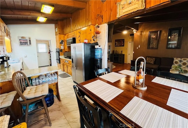 kitchen with marble finish floor, appliances with stainless steel finishes, light countertops, and wood walls