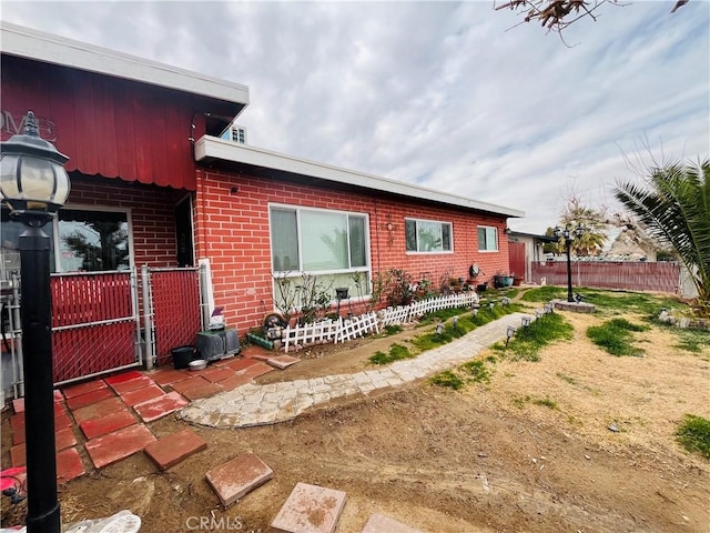 view of property exterior featuring fence and brick siding