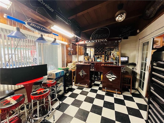 bar with a dry bar, wood walls, beam ceiling, and tile patterned floors