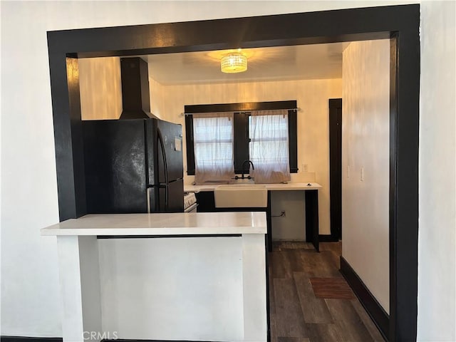 kitchen with a kitchen bar, black refrigerator, dark hardwood / wood-style floors, and kitchen peninsula