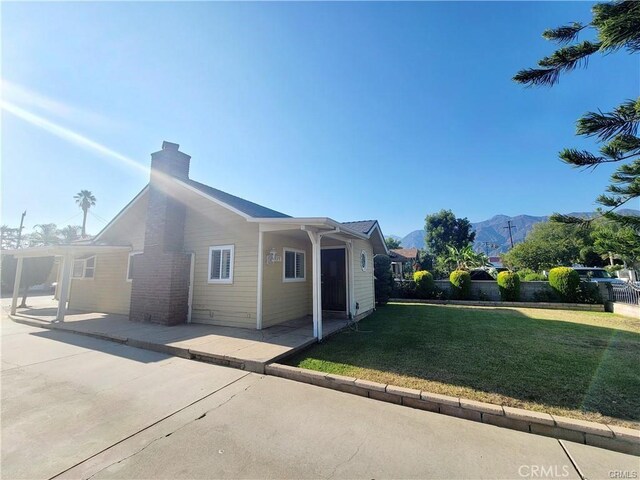 rear view of property with a pergola, a patio area, a mountain view, and a yard