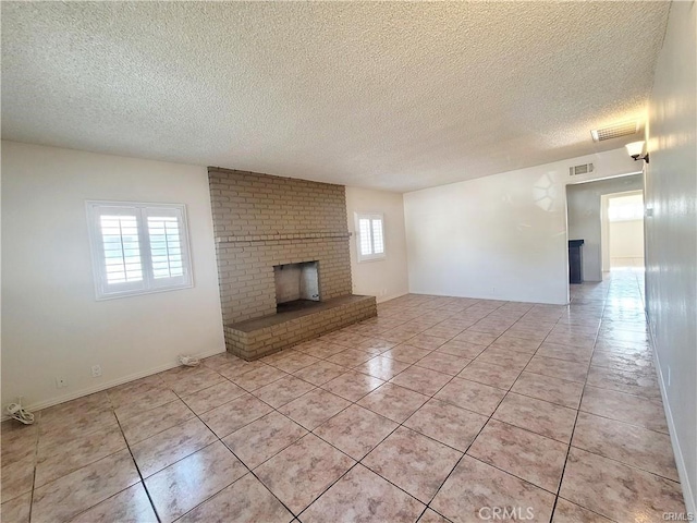 unfurnished living room with a brick fireplace, a textured ceiling, and light tile patterned flooring